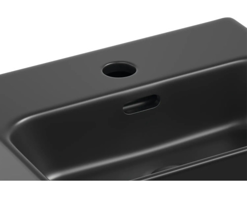 Detaljvy av ett svart tvättställ med kranhål och överlopp