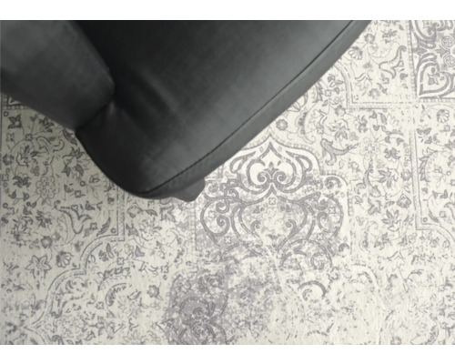 Närbild av en matta med blommönster och en del av en fåtölj