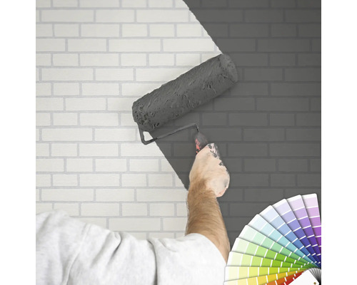 "En person målar en tegelvägg med en färgroller