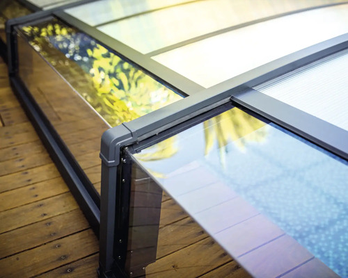 Detaljvybild av ett pooltak i glas och aluminium på ett trädäck.