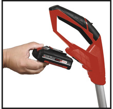 Hand håller Einhell Power X-Change-batteri vid rött trädgårdsredskapshandtag