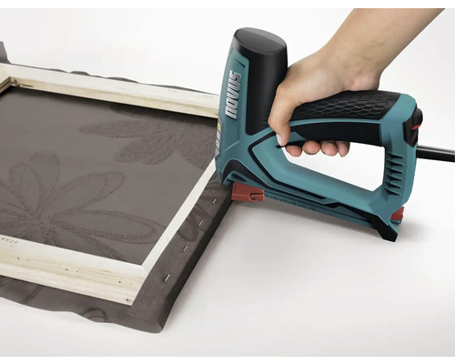 En hand använder en elektrisk häftpistol för att fästa tyg på en ram