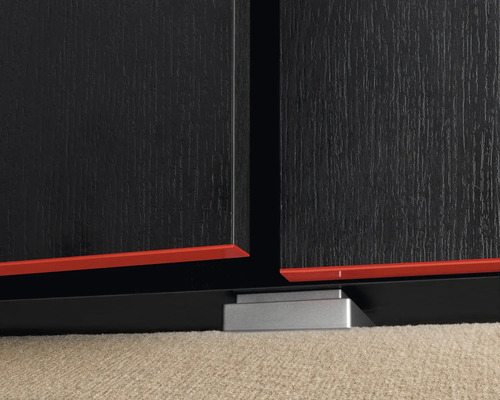 Detaljvy av en svart möbel med röda accenter och silverfärgade fötter