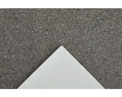 Närbild av en bänkskiva med en spräcklig yta och en vit platta