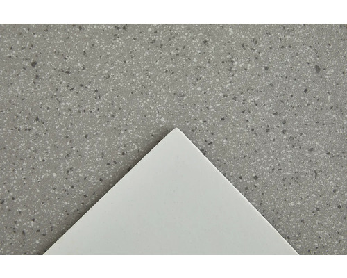 Närbild av en bänkskiva med en spräcklig yta och en vit platta