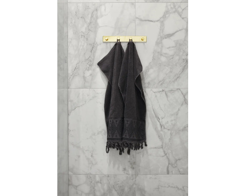 Två grå handdukar hänger på en gyllene handdukshängare i badrummet.