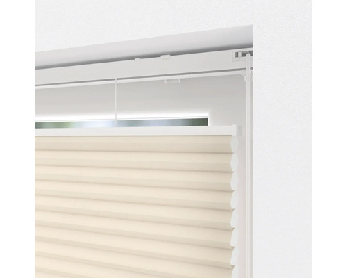 Närbild av en beige plisségardin vid fönstret