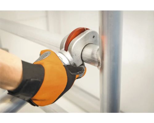 En person fäster ett ställningsrör med en rörkoppling