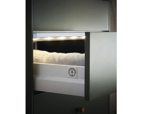 Öppet badrumsskåp med handdukar och Gustavsberg logotyp