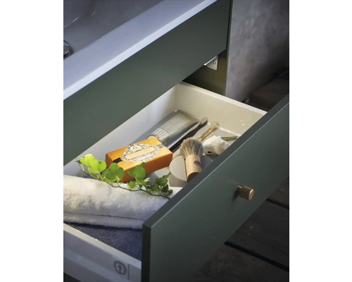 Badrumsskåp med öppen låda, fylld med handdukar och vårdprodukter