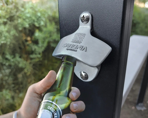 Bild på en flasköppnare på en staketstolpe som används för att öppna en glasflaska.