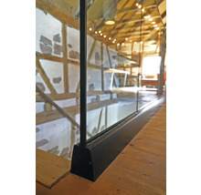 Detaljbild av en glasbalustrad med trägolv i ett hus med korsvirkesarkitektur.