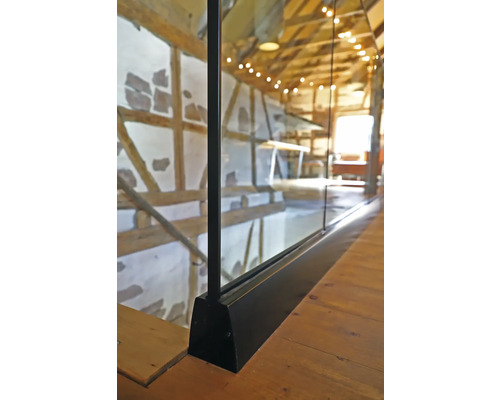 Detaljbild av en glasbalustrad med trägolv i ett hus med korsvirkesarkitektur.