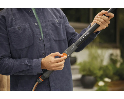 Person reglerar trädgårdsslang på ett teleskopiskt munstycke