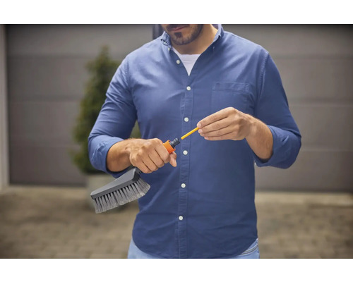 Man monterar en rengöringsborste på en trädgårdsslang