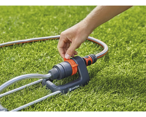 Gardena sprinkler med slang på gräsmatta
