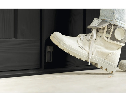 Person öppnar en svart ytterdörr med vridknapp med foten