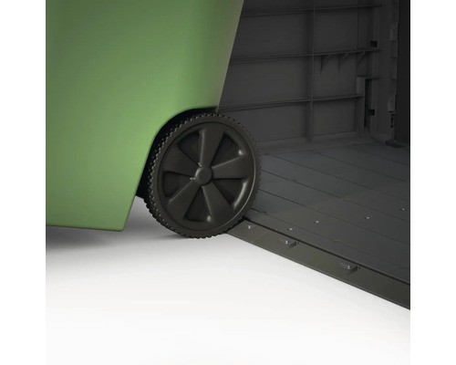 Detaljbild av en grön soptunna med hjul, placerad i ett grått redskapsbod