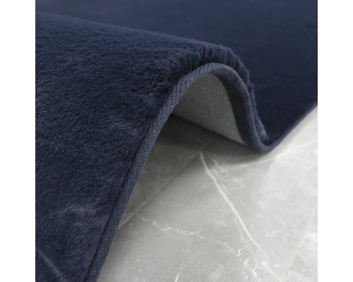 Detaljvy av en mörkblå matta med lugg på en grå bakgrund