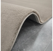Detaljvy av en beige matta med hög lugg.