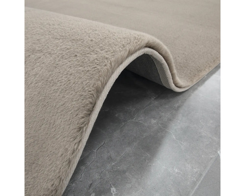 Detaljvy av en beige matta med hög lugg.