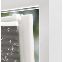 Detaljvy av en grå plisségardin med växtmönster på fönstret