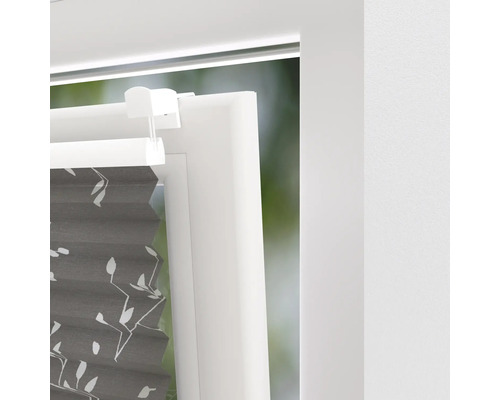 Detaljvy av en grå plisségardin med växtmönster på fönstret