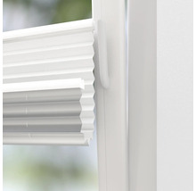 Närbild av en vit plisségardin på ett fönster