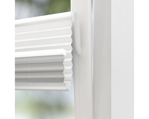 Närbild av en vit plisségardin på ett fönster