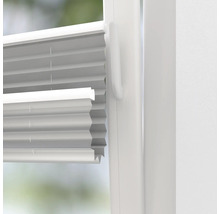 Närbild av en vit plisségardin på ett fönster