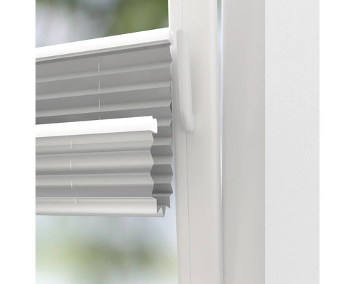 Närbild av en vit plisségardin på ett fönster