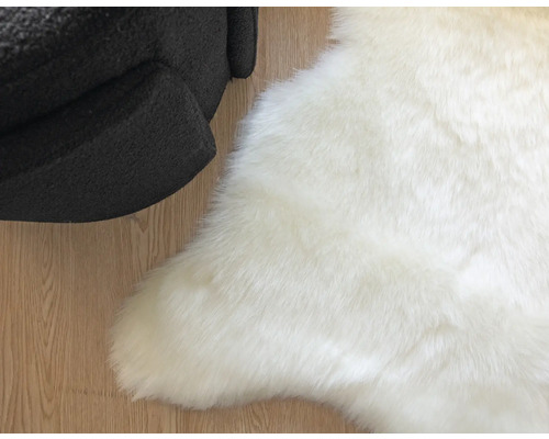 Vit fuskpälsmatta bredvid en fåtölj