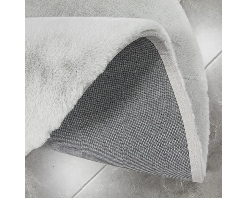 Detaljvy av en ljus matta med lugg och textilbaksida