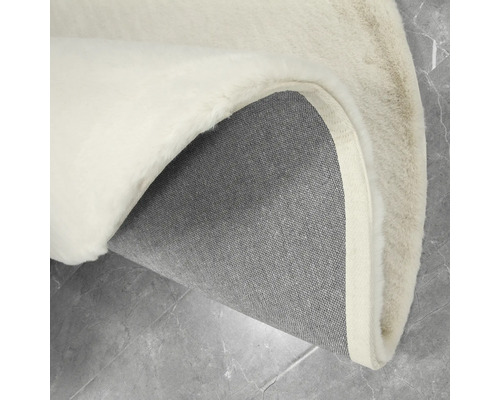 Detaljvy av en rund matta med lugg och textilbaksida