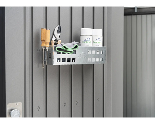 Hylla med trädgårdsredskap och sprayer på en grå vägg