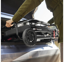 En person lastar in en Weber Traveler-grill i bagageutrymmet på en bil.