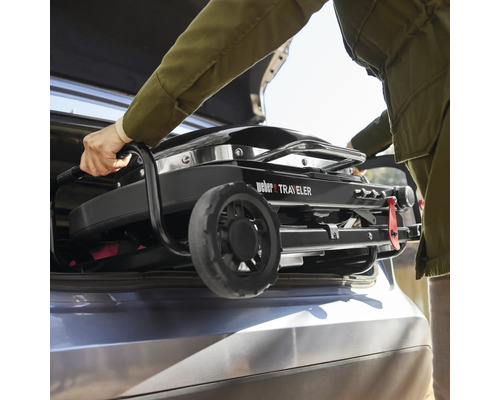 En person lastar in en Weber Traveler-grill i bagageutrymmet på en bil.