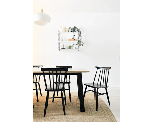 Matsal med träbord, svarta stolar och vägghylla