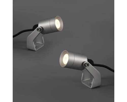 Två silverfärgade trädgårdsstrålkastare med kabel