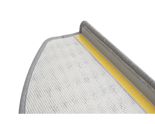 Detaljvy av ett grått trappsteg med textilbeläggning och självhäftande remsor för fastsättning.