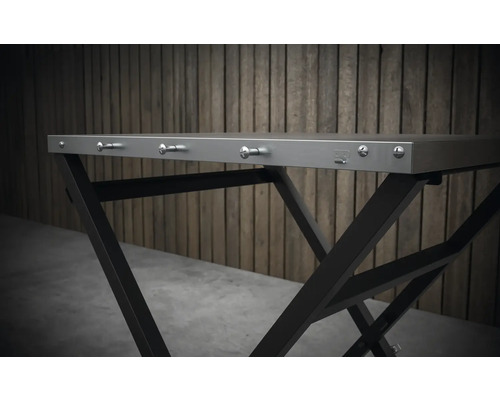 Detaljvy av ett fällbart bord med metallram och krokar