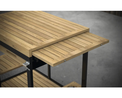 Detaljvy av en serveringsvagn i teak med utdragbar arbetsyta och förvaringsutrymmen.