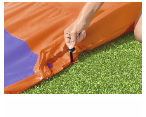 Person som fäster vattenrutschkanan med pinnar i gräsmattan