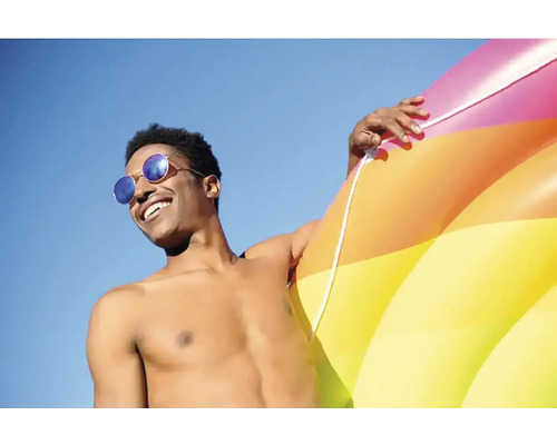 Man med solglasögon och uppblåsbar badring mot blå himmel