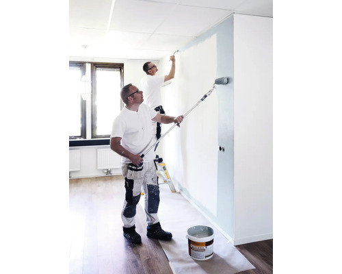 Två hantverkare målar ett rum med roller och pensel