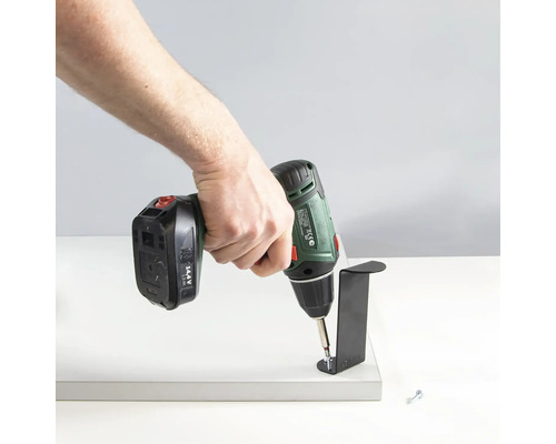 En person fäster ett fäste på en platta med en batteridriven skruvdragare.