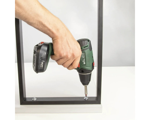 En person skruvar ihop en möbel med en sladdlös skruvdragare.