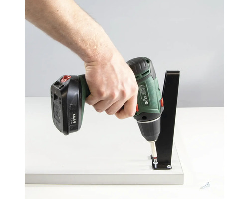 Sladdlös skruvdragare fäster ett hyllfäste på en hylla