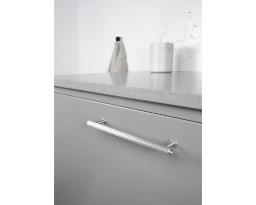 Detaljvy av en grå lådfront med ett avlångt, silverfärgat handtag