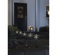 Dekorativ trädgårdsbelysning med stjärnmotiv framför ett hus med en krans på dörren